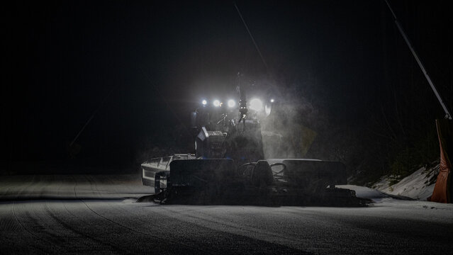 Snow-groomers work in nighttime on ski resort.