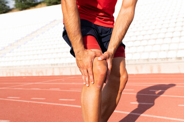 An athlete with an injured knee is holding his knee. knee and joint injuries
