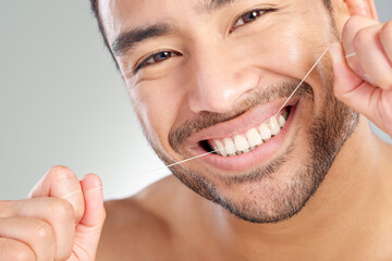Oral, floss and dental hygiene with model in studio on white background cleaning teeth for healthy gums. Man, healthcare routine and mouth portrait with guy flossing to remove plaque or gingivitis