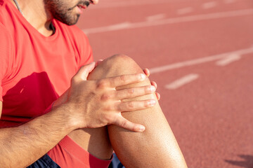 An athlete with an injured knee is holding his knee. knee and joint injuries