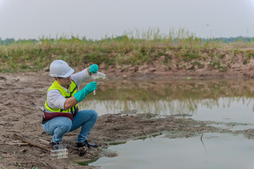 Environmental engineer Sit down next to a well and try to pouring the water from the plastic glass...