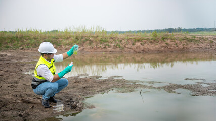 Environmental engineer Sit down next to a well while holding the plastic glass that fill with the...