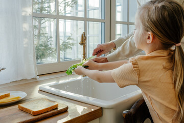 Child washing lettuce at kitchen sink