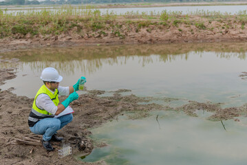 Environmental engineer Sit down next to a well while holding the plastic glass that fill with the...