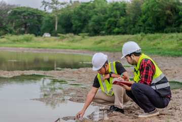 Two of environmental engineer Sit down next to a well try to scoop the water sample in a well and check water quality and contaminants in the water source.