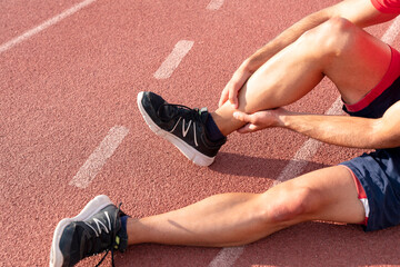 Athlete with injured ankle is holding his knee. knee and foot joint injuries