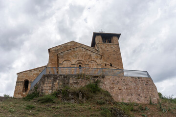Fototapeta premium A large stone building with a bell tower. The building is surrounded by a lush green hillside.