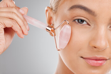 Woman, rose quartz roller and skincare in studio portrait for facial wellness, and clean by white...
