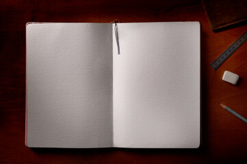 Blank notebook with a pencil and eraser on a wooden table