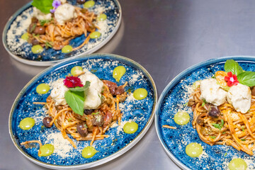 four plates of spaghetti with meat and cheese on top on a table