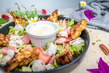 a bowl filled with chicken next to vegetables and garnished with sauce