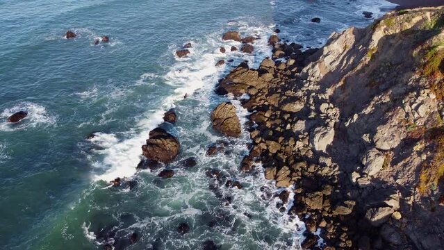 Drone shot of sea waves crashing the rocky California coastline near bodega bay on a sunny day