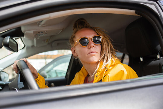 Pretty woman in yellow raincoat wearing sunglasses with dread hairstyl