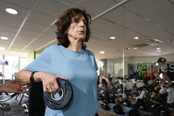 Senior woman exercising with weights at gym