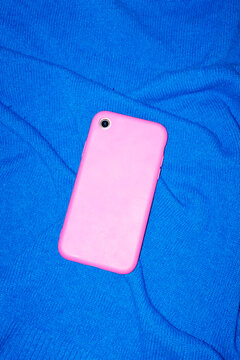 Pink modern smart phone on blue background with direct flashlight