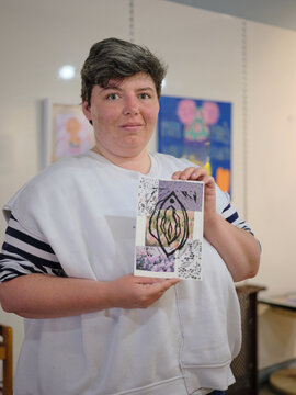 Young autistic artist at gallery holding her artwork