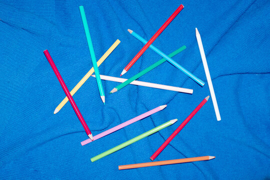 Colorful pencils on blue background with direct flashlight