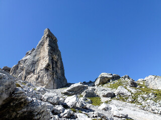 A view of the rocks of the mountains under a clear blue sky. View from below. Mountain summer tourist landscape