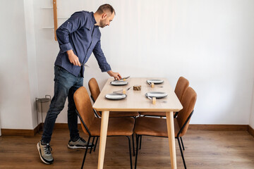 young man working in a restaurant arranging the tables