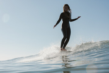 young woman surfing on long board on sunny day