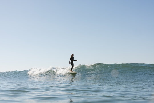 young woman surfing on long board on sunny day