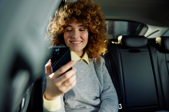 Smiling woman looking at her phone in the car