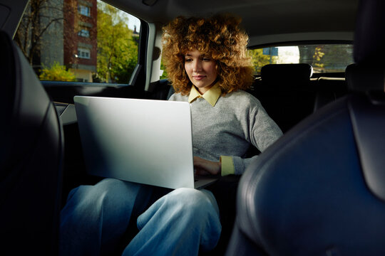 Young woman works in the back of the car