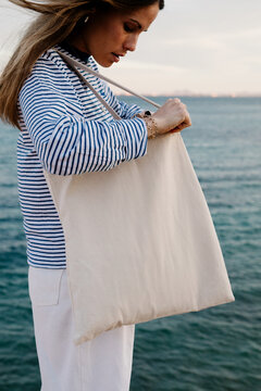A medium shot capturing a young woman clutching a plain white tote bag