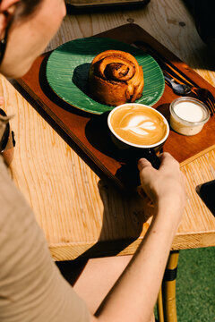 A cyclist having a flat white and cinnamon roll for breakfast