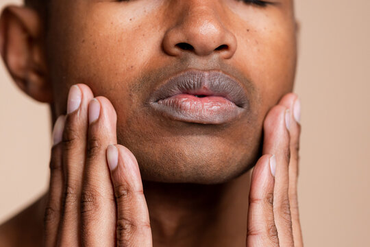Close-up of man's lips and hands on face