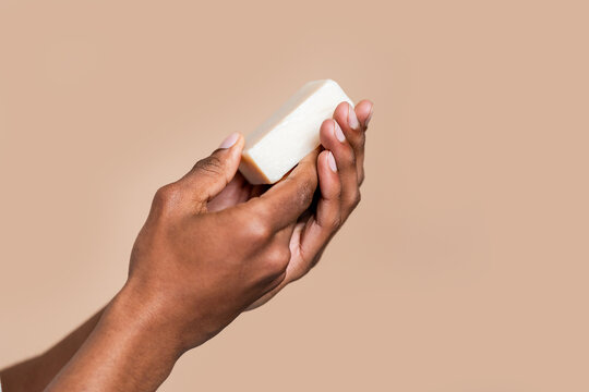 Hand holding a bar of soap against a neutral background