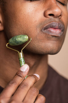 Young man using jade roller on face