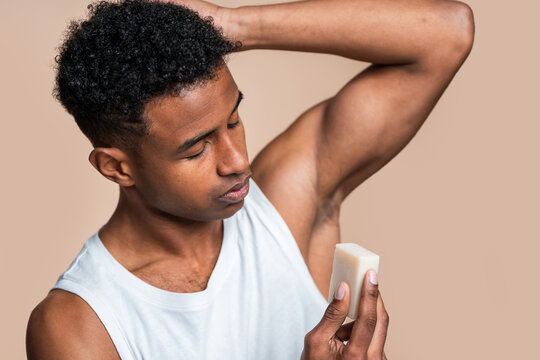 African american man in a white tank top applying stick deodorant