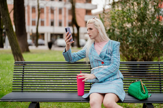 A non-binary man sitting on a bench at the city park