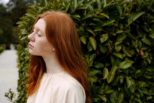 Profile of redhead woman against greenery