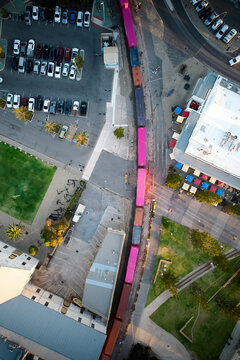 Urban rail freight train hauls cargo containers, overhead aerial