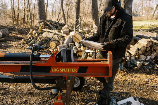 millennial man standing in his backyard making firewood