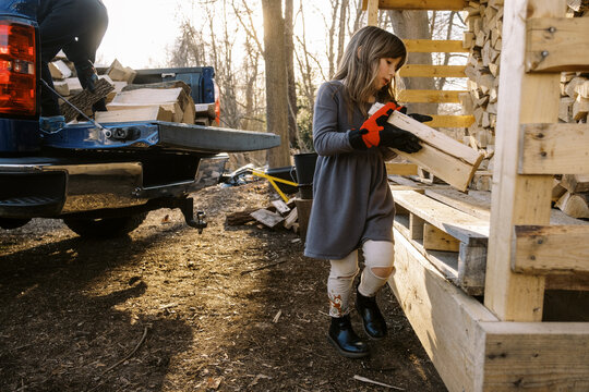 children helping with to stack firewood in backyard