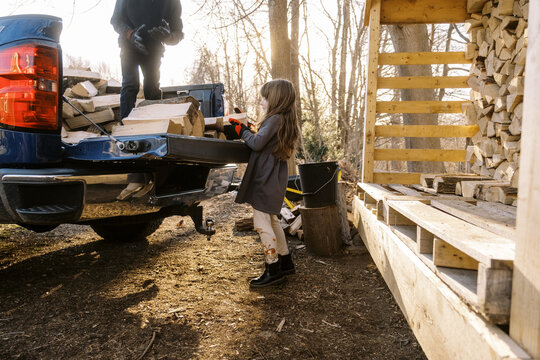 children helping with to stack firewood in backyard