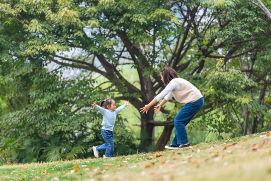 side view of happy asian kid running to her mother in the spring park