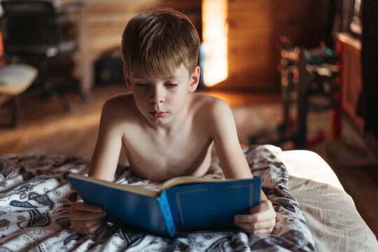 Young Boy Engrossed in Reading a Book Indoors