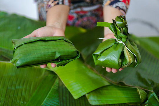 Woman holding a tamal in each hand
