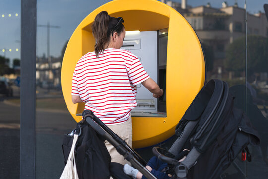 Mother Using ATM with Stroller Beside