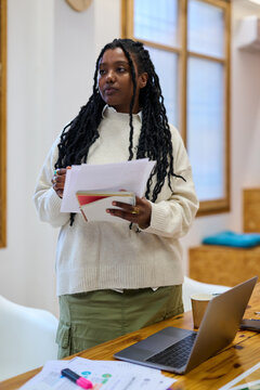 Black young intern standing listening and writing notes
