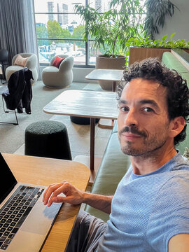 Selfie of a man sitting in front of his laptop in a co-working space