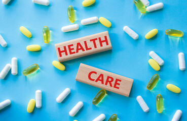 Healthcare symbol. Wooden blocks with words Healthcare. Beautiful blue background with pills....