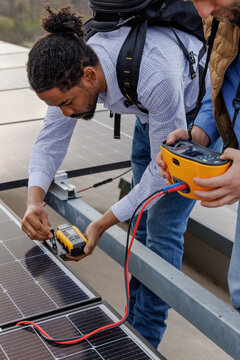 Male engineers using equipment on solar panel