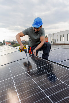 Male engineer installing solar panels on rooftop