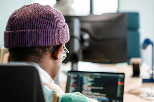 A man is programming on a laptop in the office