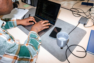 A man is programming on a laptop in the office